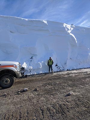 click for larger view of photo: Operator Daniel Helmer stands next to a massive snow drift at American Summit 