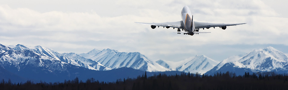 jet aircraft taking off from ANC with mountains in the background - photo by Lex Yelverton