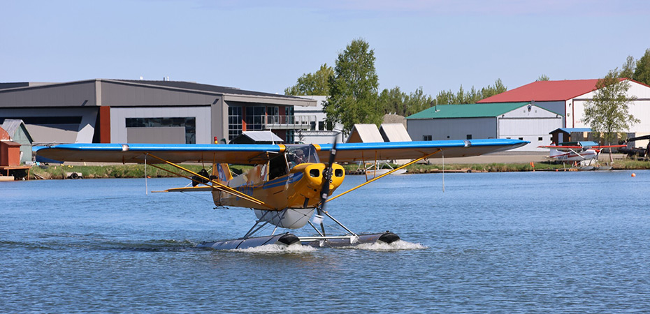 Float plane taxiing on the waters of Lake Hood
