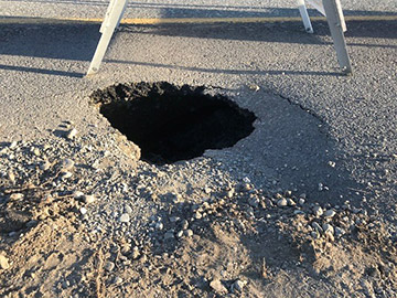 Pothole along Point MacKenzie Road due to material loss near a damaged culvert.