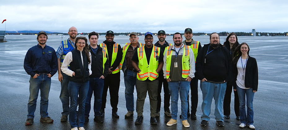 Group photo of the operations team next to an official vehicle on the tarmac at Fairbanks International Airport
