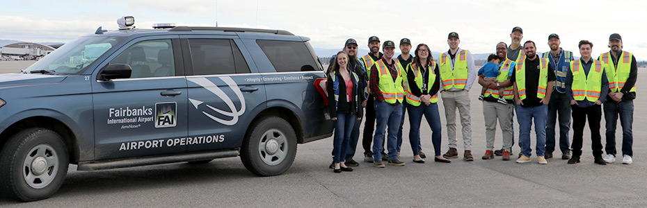 Group photo of the operations team next to an official vehicle on the tarmac at Fairbanks International Airport