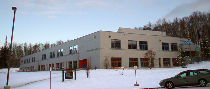 Outdoor photo showing Pearl Creek Elementary School with snow on the ground and a car parked