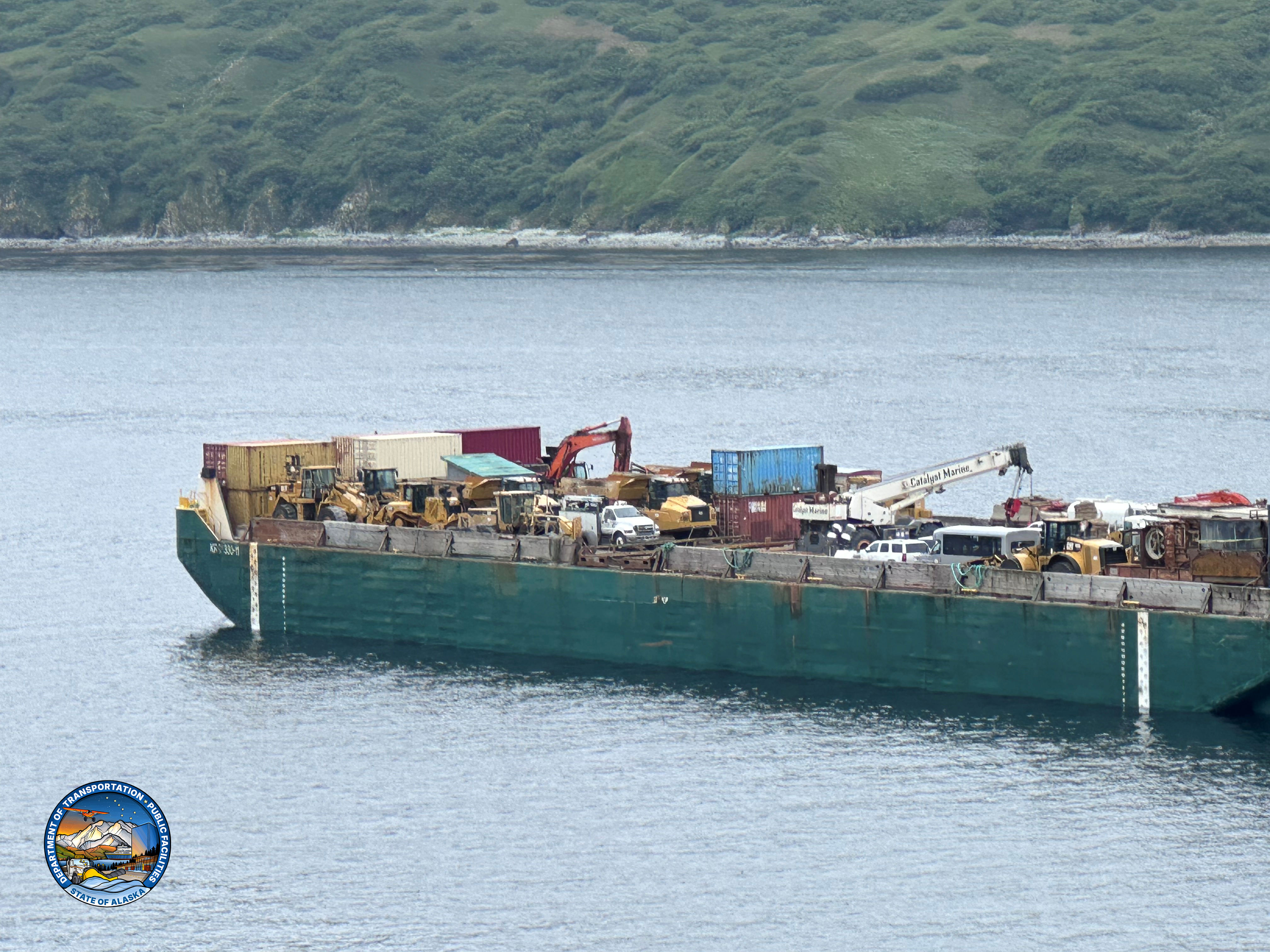 A barge arrives in King Cove with equipment and materials