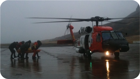 Coast Guard Helicopter being loaded with a medevac patient in poor weather
