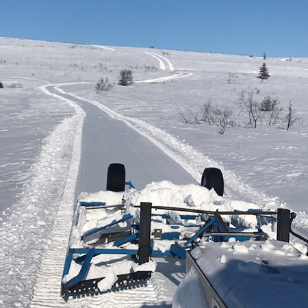 snowmachine trail grooming on gentle rolling hills